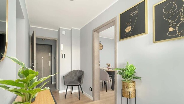 Un couloir moderne avec un plancher en bois, une chaise grise et une plante en pot.