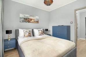 Un dormitorio con cama, mesitas de noche, un armario y un cuadro en la pared.