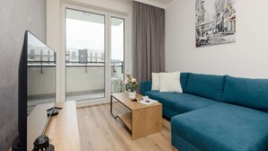 Ein modernes Wohnzimmer mit einem blauen Sofa, einem Holztisch, einem Flachbildfernseher und einem Stadtbild an der Wand.