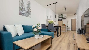 Ein modernes Wohnzimmer mit einem blauen Sofa, einem Holztisch und einem Essbereich mit Stühlen und einem Tisch.