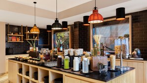 Une cuisine moderne dotée d’un îlot central, de plans de travail noirs, d’étagères en bois et de luminaires suspendus.