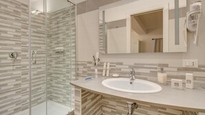 A modern bathroom with a glass shower enclosure, a white sink, and a large mirror. - Roma Suites Navona (Rome)