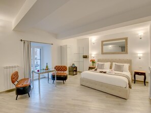 A bedroom with a large bed, a bedside table, a chair, a small table, a mirror, and a window with curtains. - Roma Suites Navona (Rome)