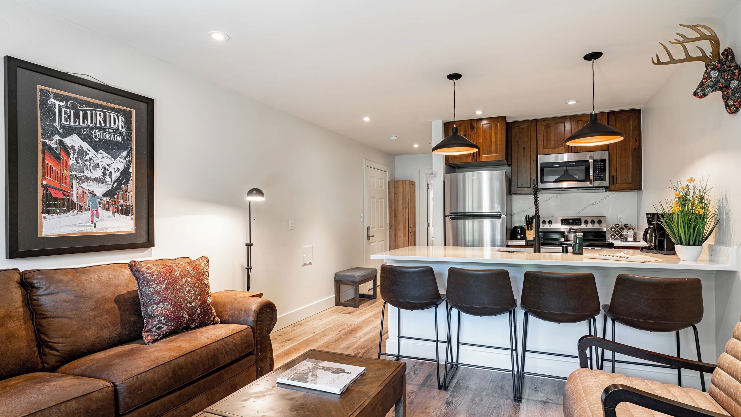 A modern kitchen with stainless steel appliances, a bar area, and a cozy living room with a leather sofa.