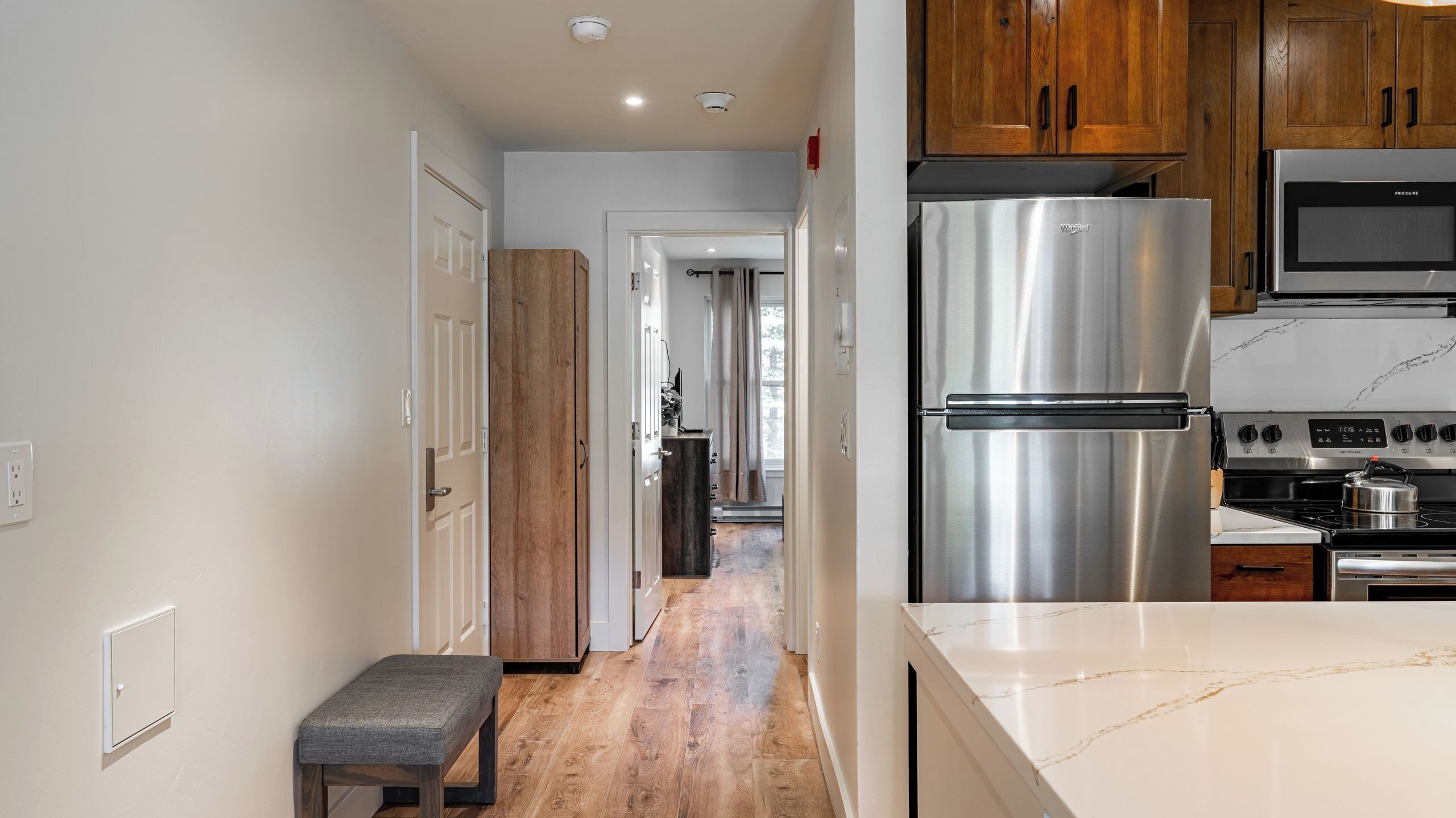 A modern kitchen with stainless steel appliances, wooden cabinets, and a marble countertop.