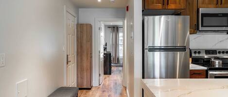 Una cocina moderna con electrodomésticos de acero inoxidable, armarios de madera y encimera de mármol.