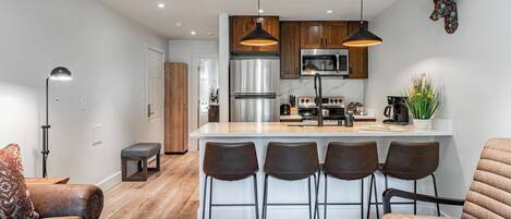 A modern kitchen with stainless steel appliances, a central island with bar stools, and a decorative deer head on the wall.