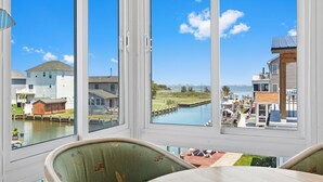 Ein Zimmer mit großem Fenster und Blick auf einen Kanal, Boote und Gebäude.