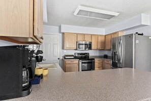 A modern kitchen with granite countertops, stainless steel appliances, and wooden cabinets.