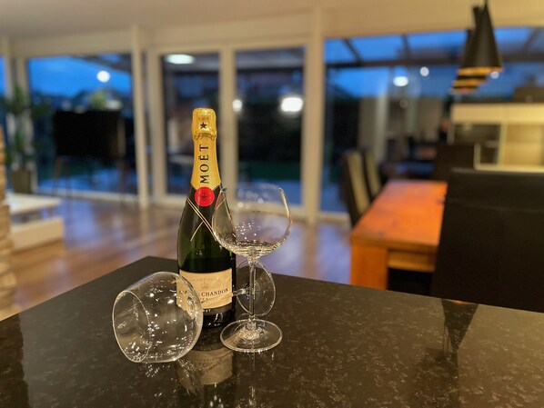 A bottle of Moët & Chandon champagne and two glasses on a marble table in a modern living room with large windows.