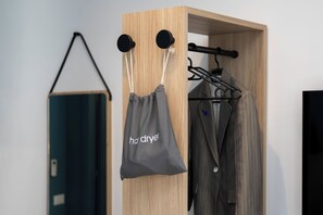 A wooden wardrobe with a hanging bag labeled "ha drye!" and a coat hanger with a striped coat.