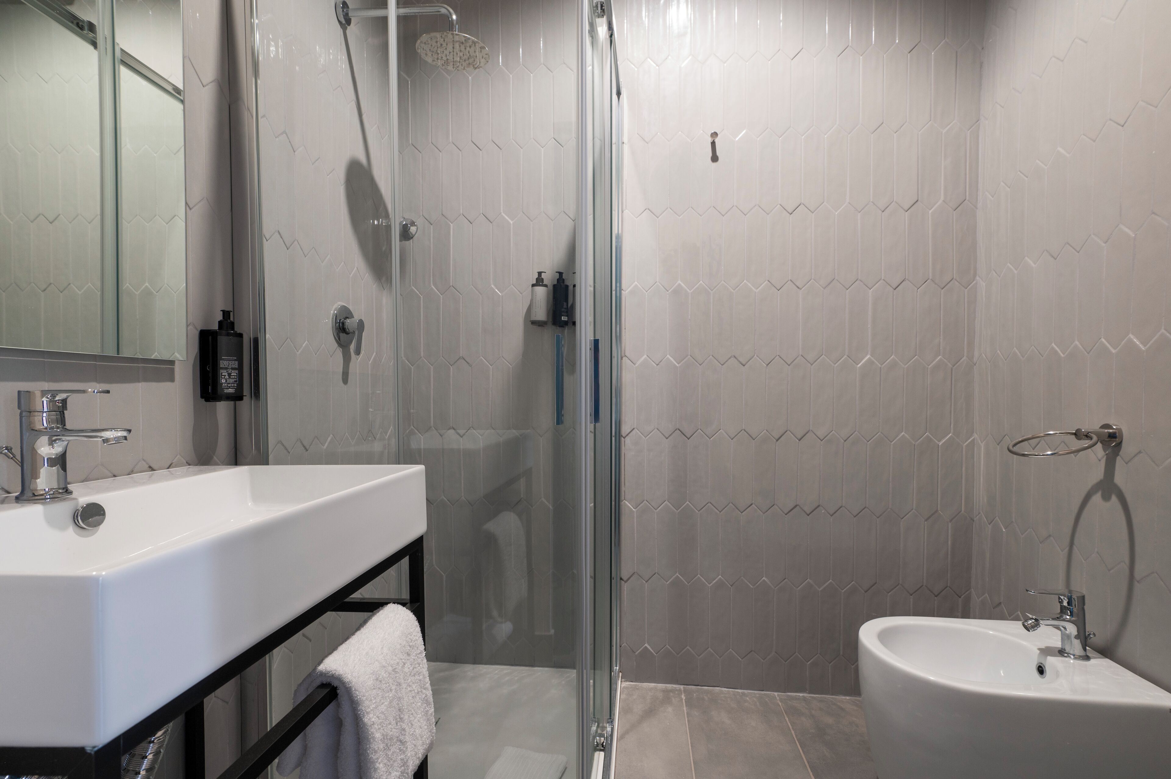 A modern bathroom with a glass-enclosed shower, a white sink, and a bidet.