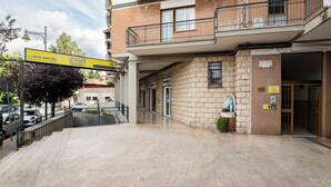 L’entrée d’un hôtel, avec une façade en pierre, un balcon doté d’une balustrade en métal et une enseigne publicitaire.