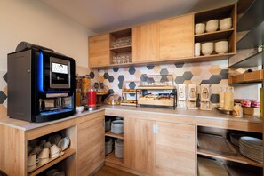 A modern kitchen with a coffee machine, shelves with plates and bowls, and a hexagonal tile backsplash. - Rome Ciampino Smart Hotel (Ciampino)