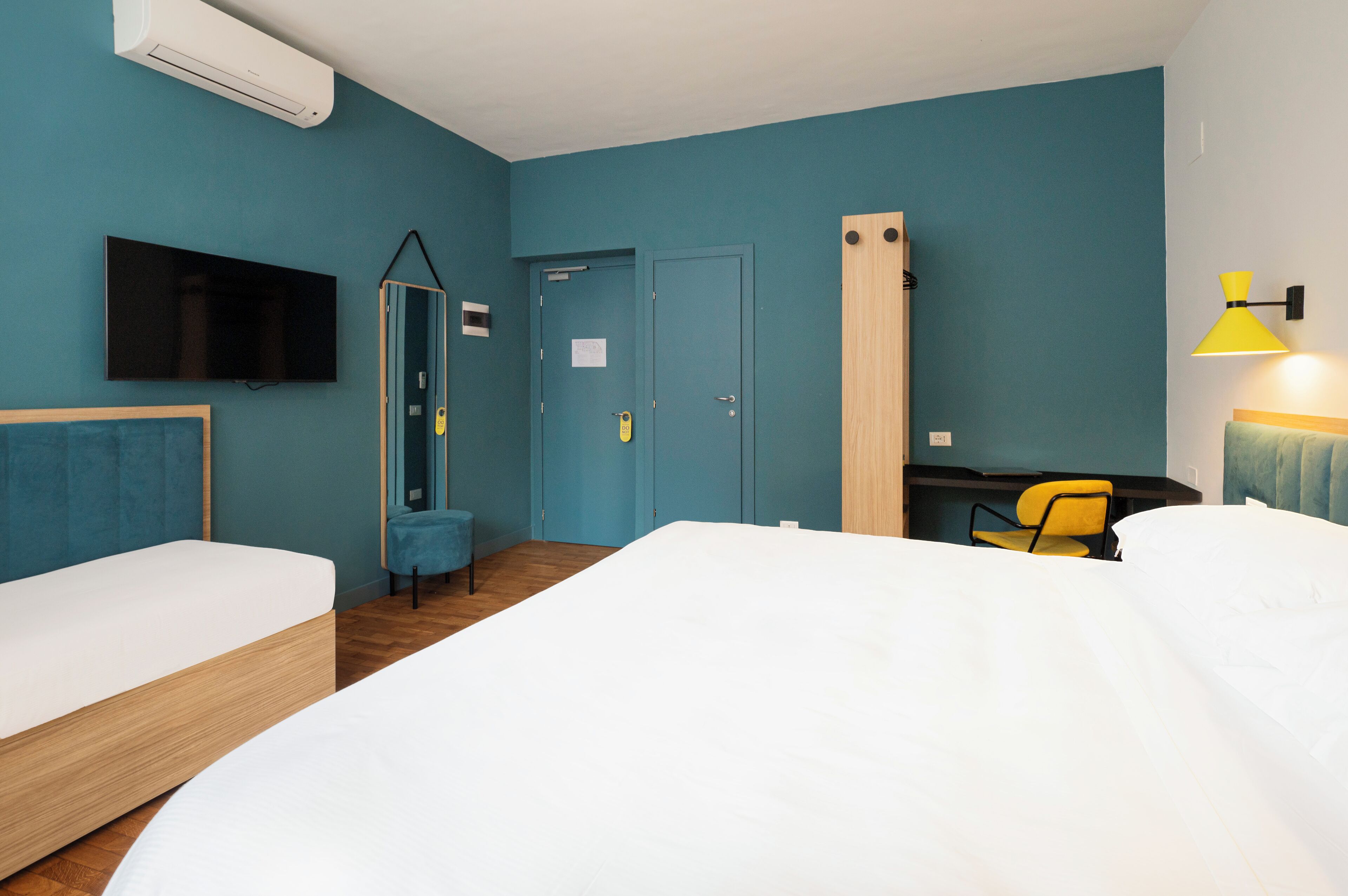 Habitación de hotel con dos camas, televisión, escritorio, silla y puerta.