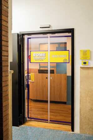 A hotel entrance with a 'ROME CIAMPINO SMART HOTEL' sign, a reception desk, and a wooden floor. - Rome Ciampino Smart Hotel (Ciampino)