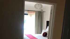 Une chambre d’hôtel avec un lit, une fenêtre avec des rideaux et un sol carrelé.