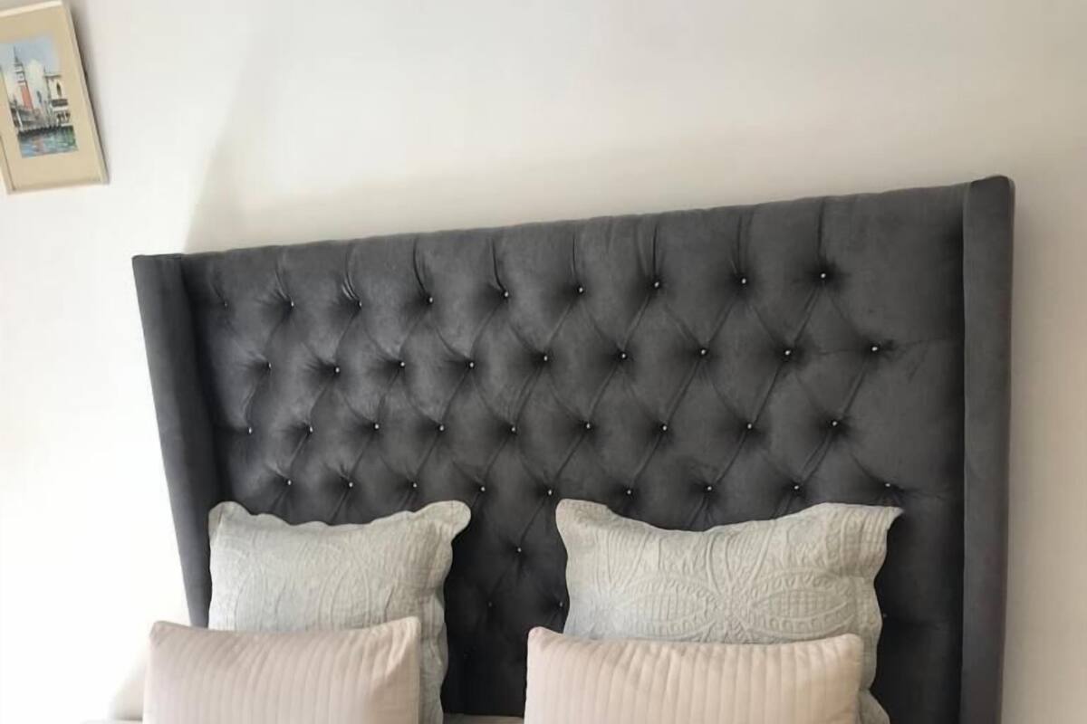 A bed with a tufted headboard, two pillows, and a red blanket.