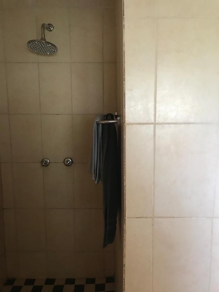 A bathroom with a shower, tiled walls, and a towel hanging on a rack.