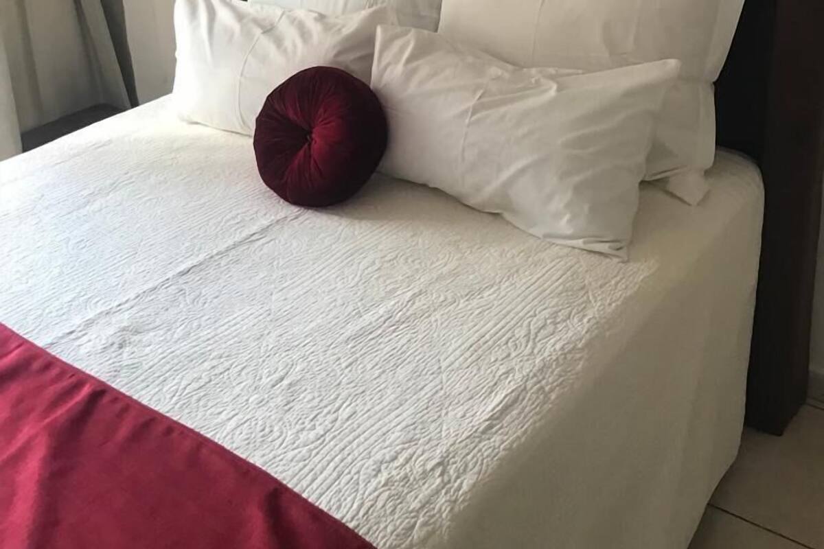 A neatly made bed with a dark headboard and white bedding.