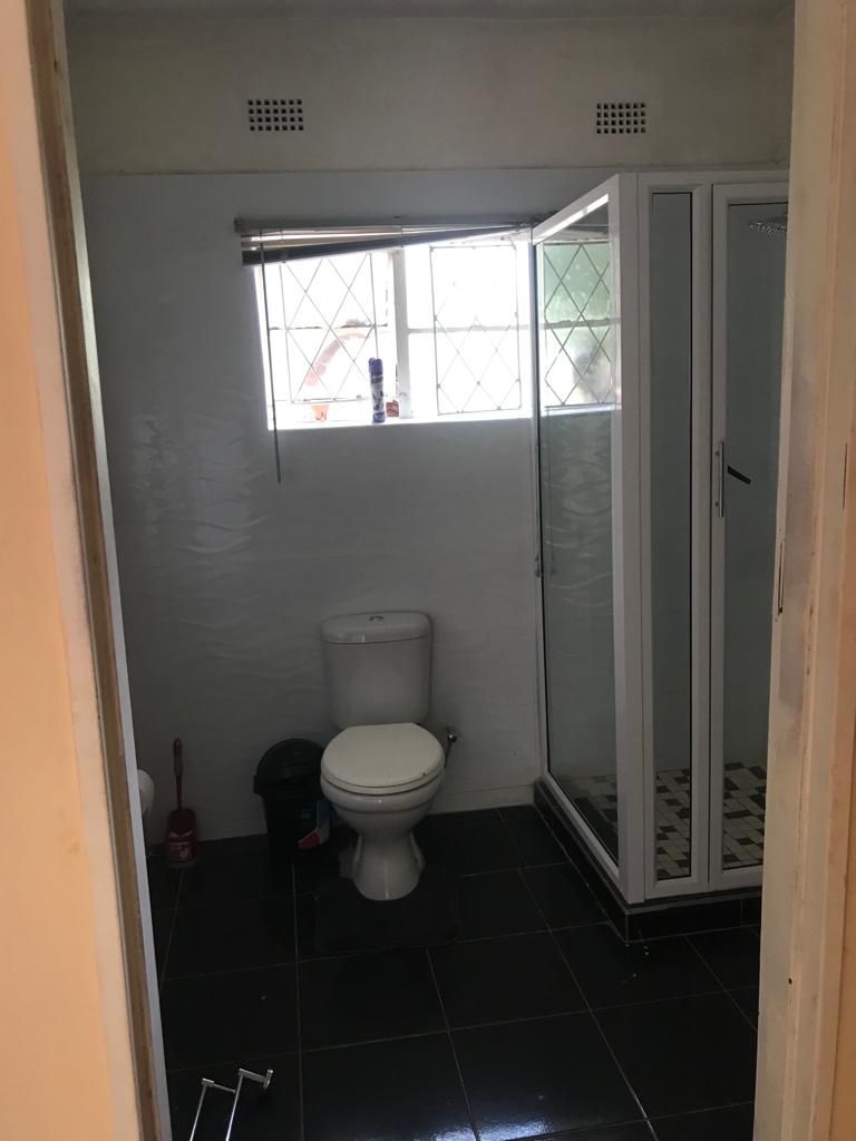 Une petite salle de bain comprenant des toilettes, un espace douche et une fenêtre.