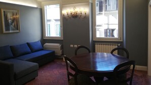 Un comedor con mesa y sillas de madera, un sofá azul y un radiador.
