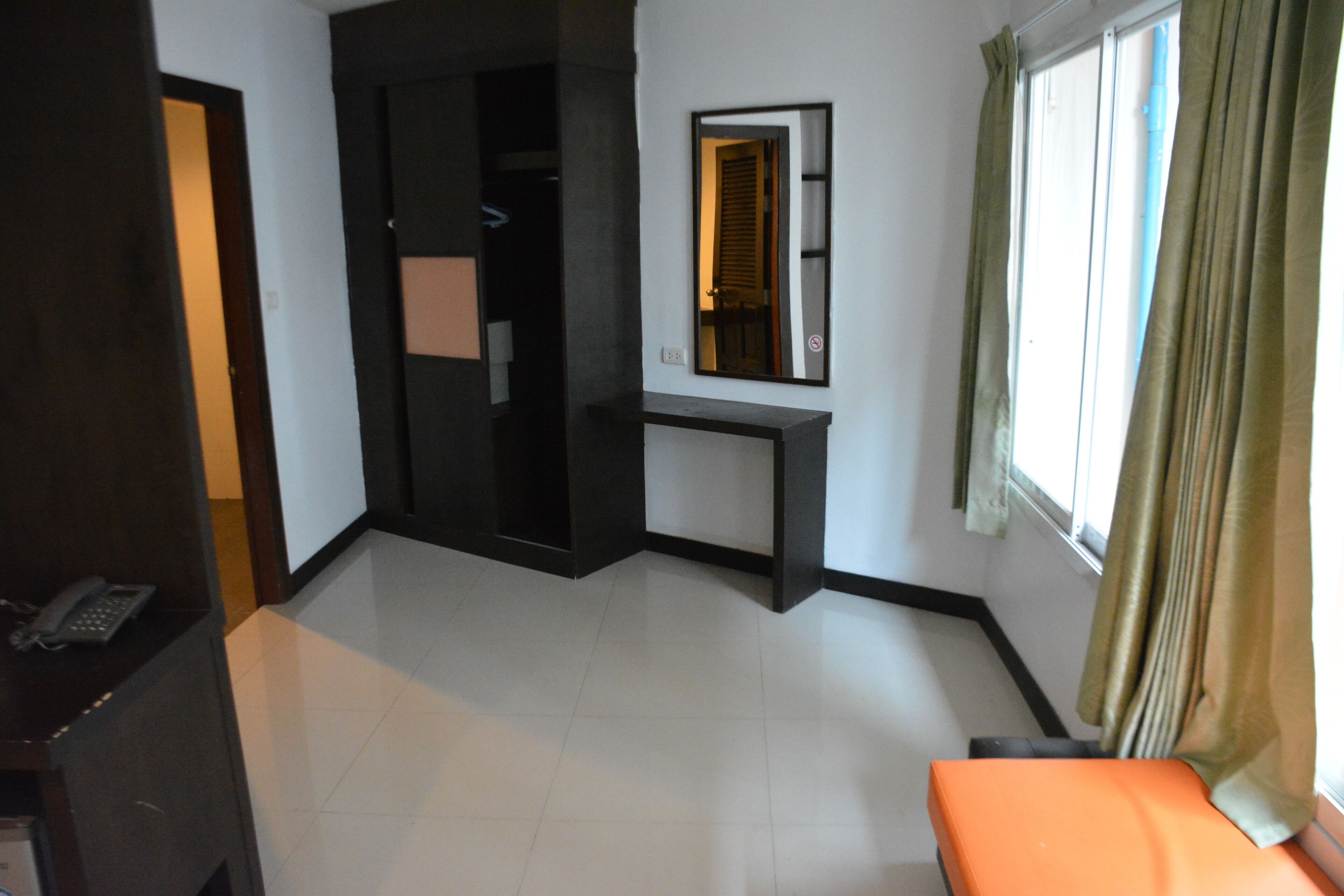 A hotel room with a bed, a desk, a chair, a phone, and a window with curtains.