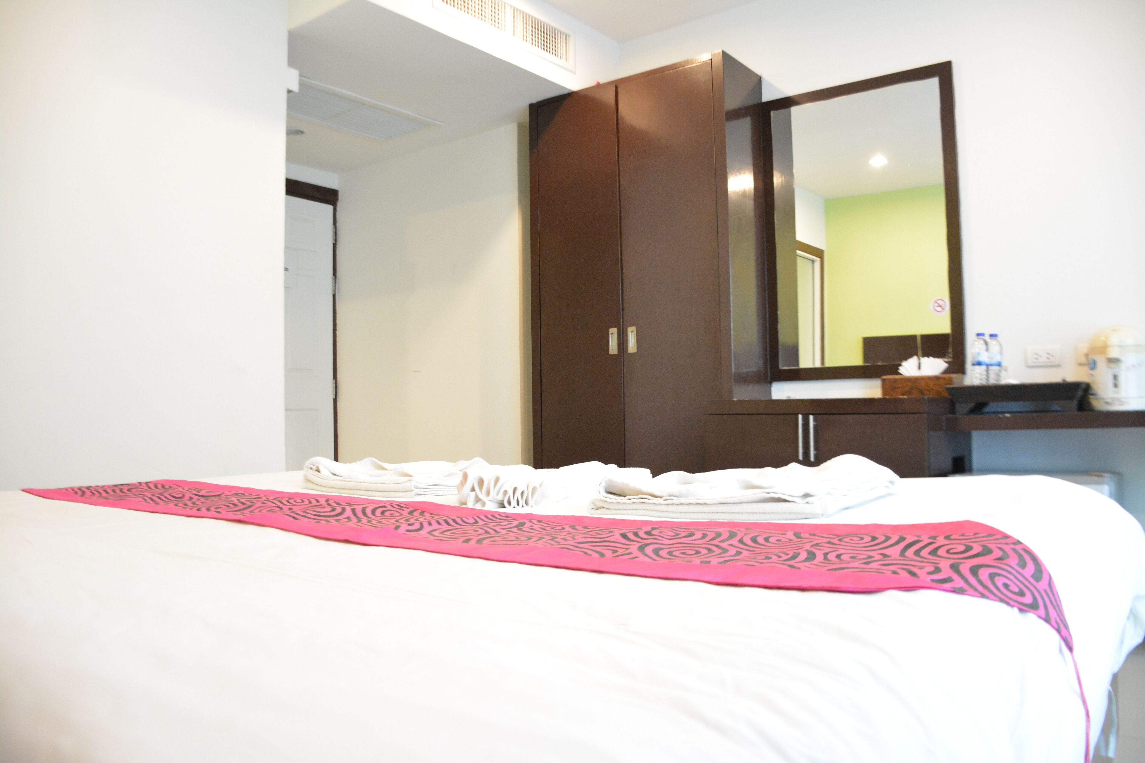 Habitación de hotel con cama, un espejo grande, un armario y una mesita con artículos de aseo.