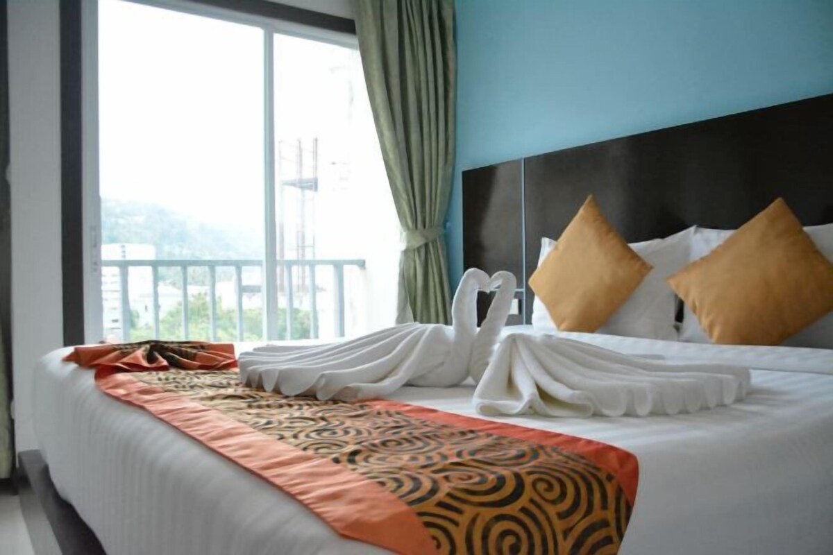 A hotel room with a large bed, a view of the outdoors, and a window with curtains.