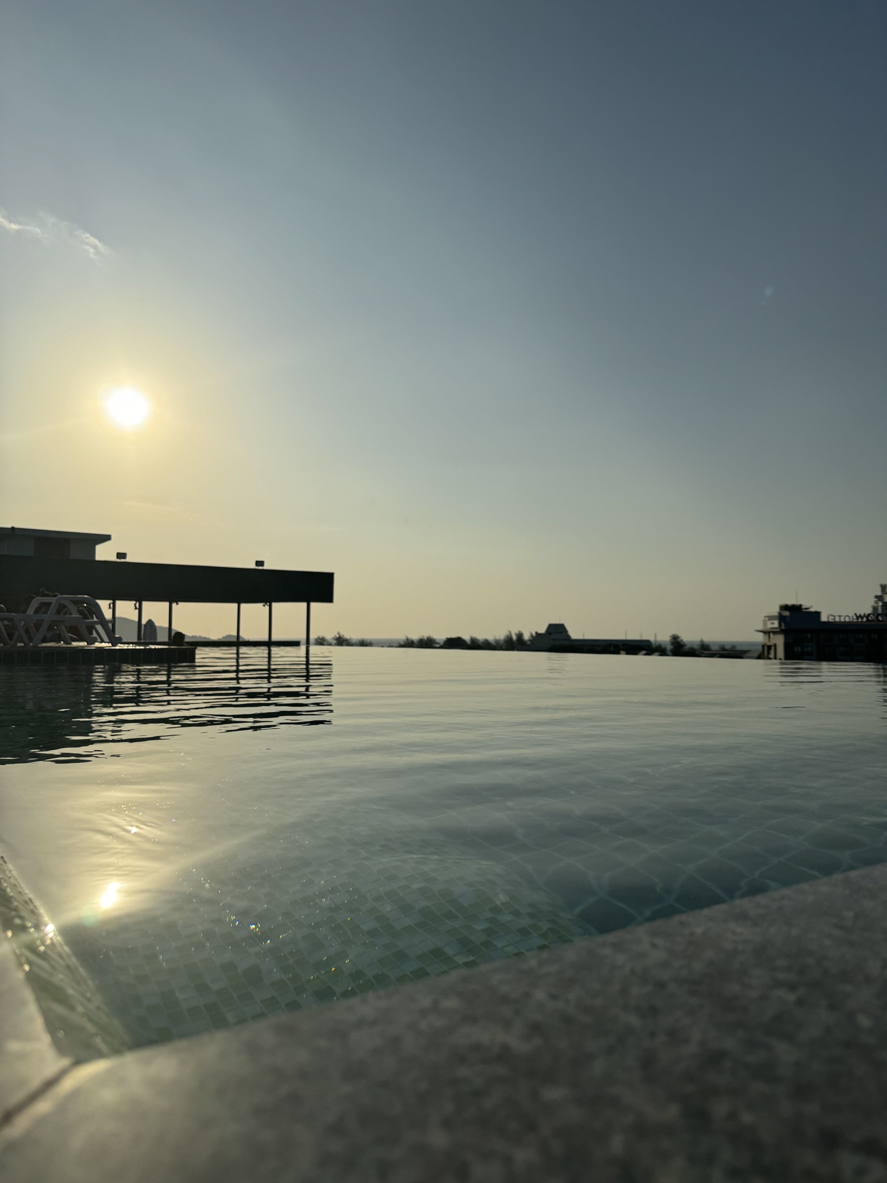 A swimming pool with a sunlit sky and distant buildings.