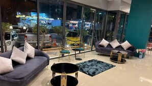 A modern living room with a sofa, two round tables, and a blue rug. - Zephyr Grand Hotel (Patong)