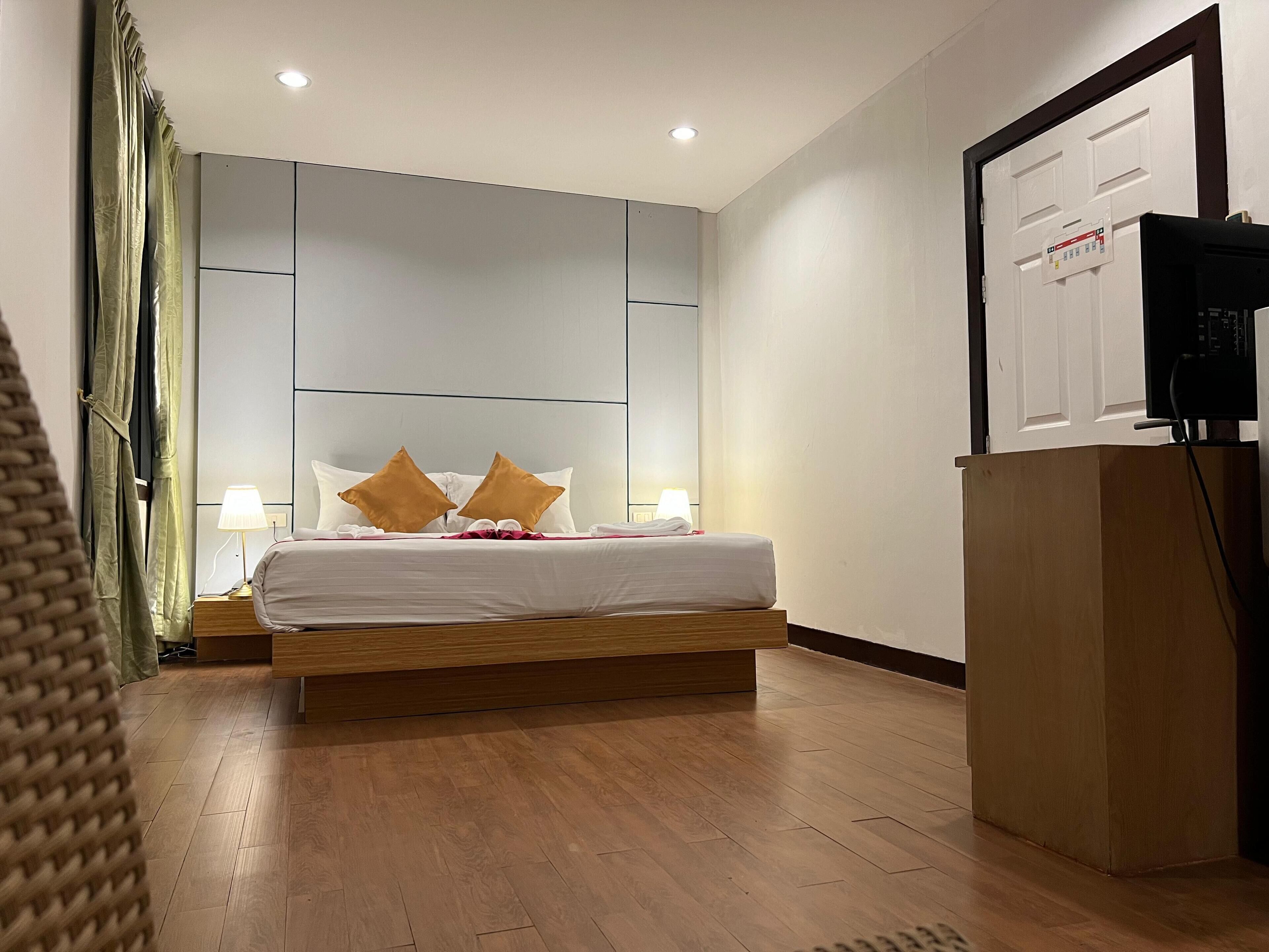 A modern hotel room with a wooden bed, two bedside lamps, and a large wall panel.