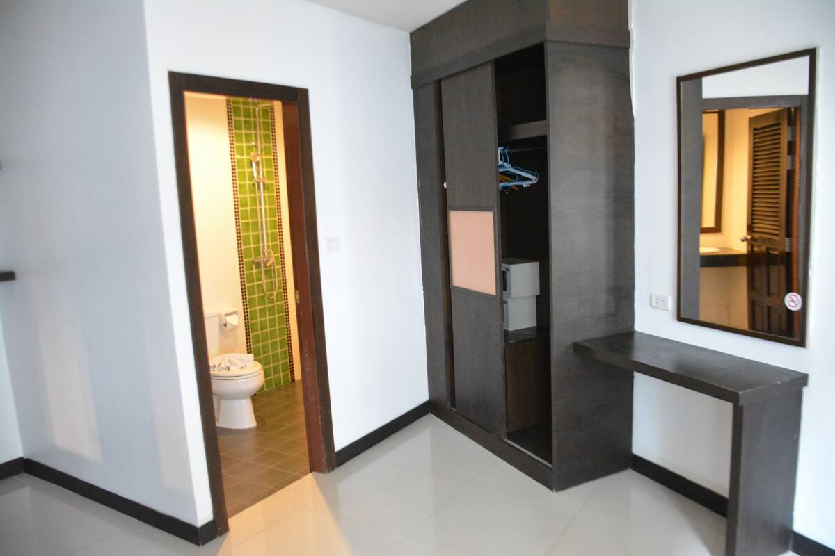 A hallway with a toilet, a mirror, and a dark-colored console table.