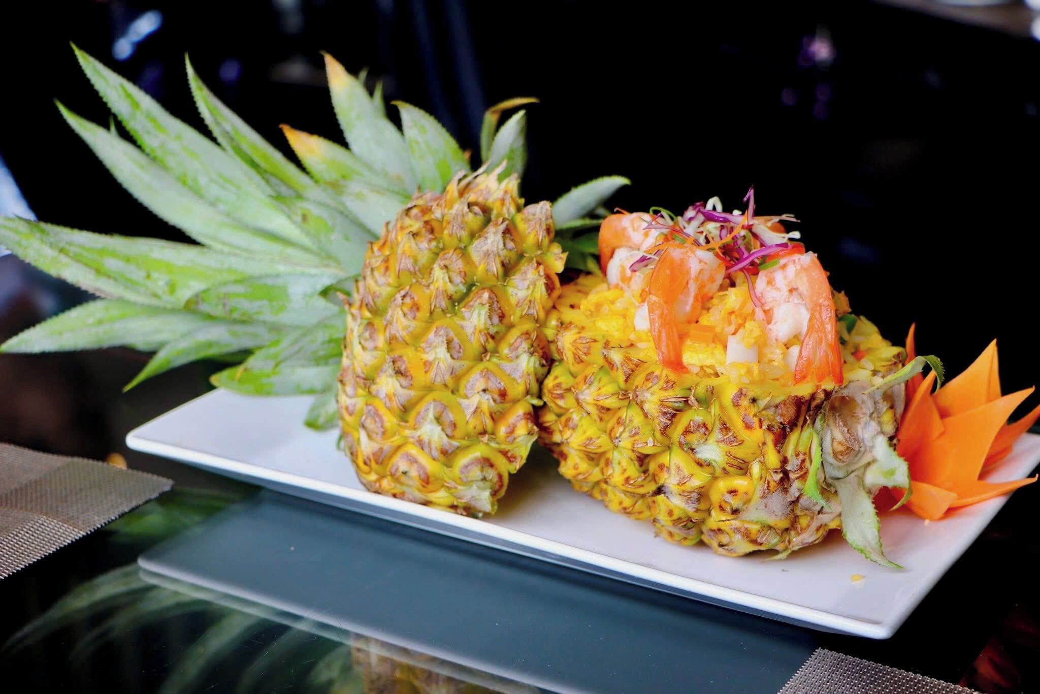 Two pineapples with shrimp on a white plate.