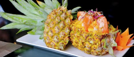 Two pineapples with shrimp on a white plate.