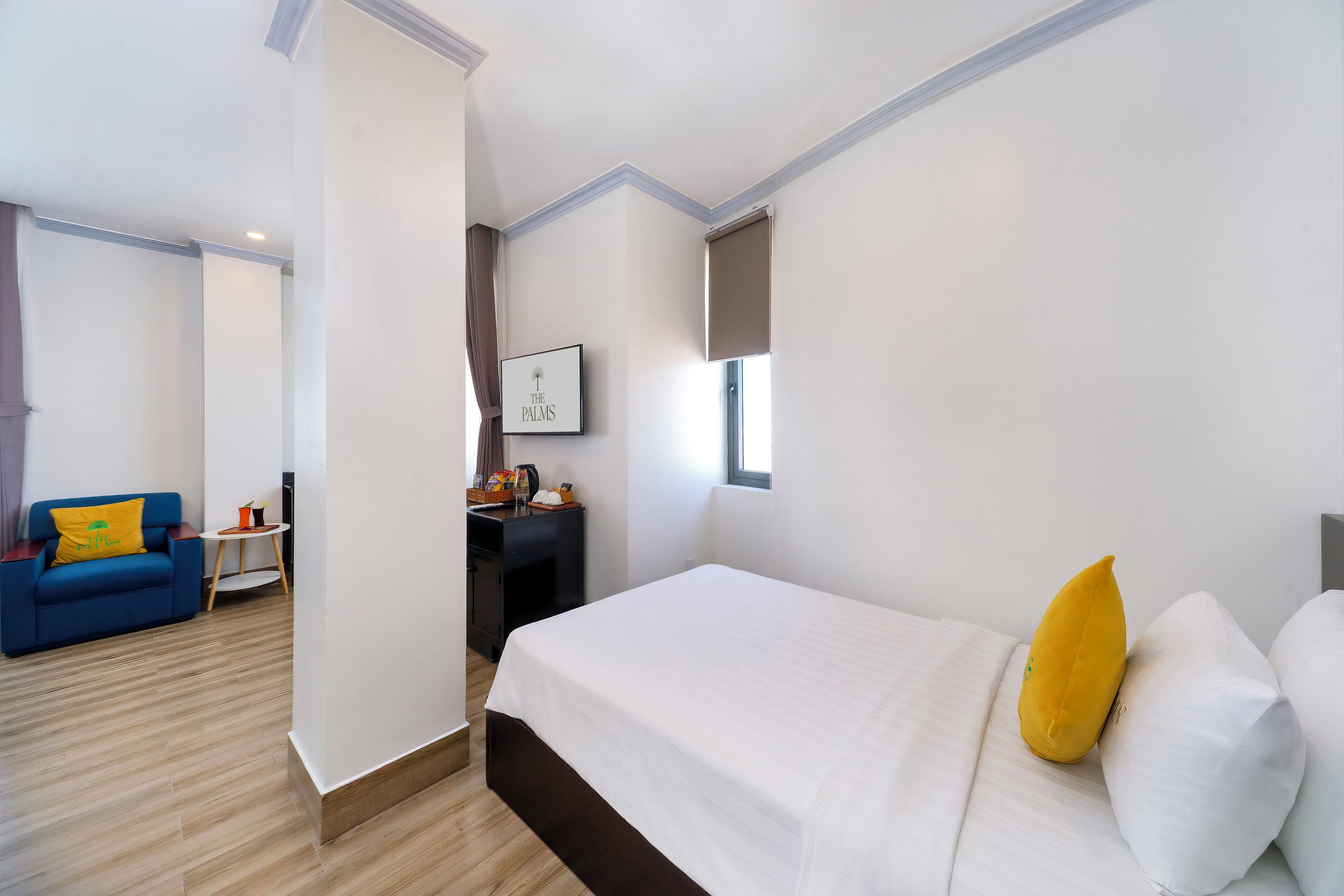 A hotel room with a bed, a blue sofa, a small table, and a wall-mounted picture.