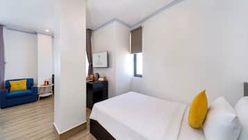 A hotel room with a bed, a blue sofa, a small table, and a wall-mounted picture.