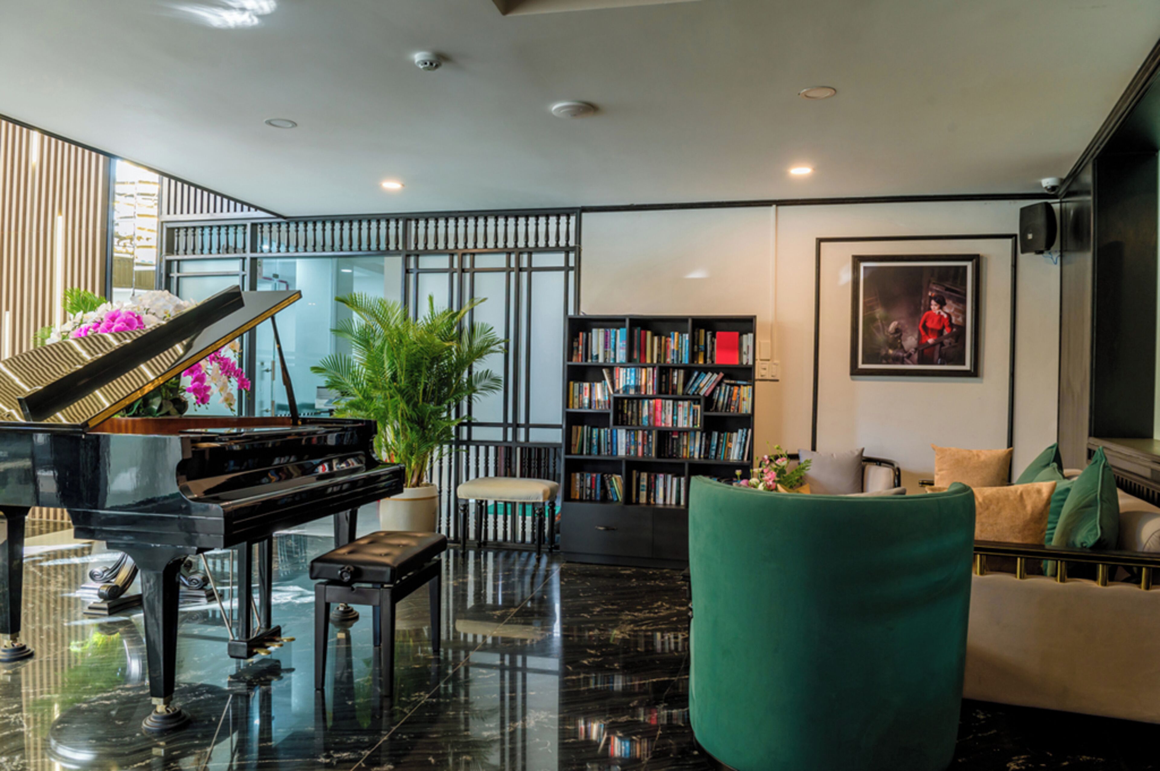 A modern living room with a grand piano, a bookshelf, a green armchair, and a sofa.