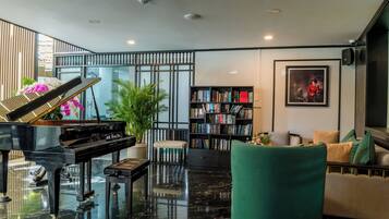 A modern living room with a grand piano, a bookshelf, a green armchair, and a sofa.
