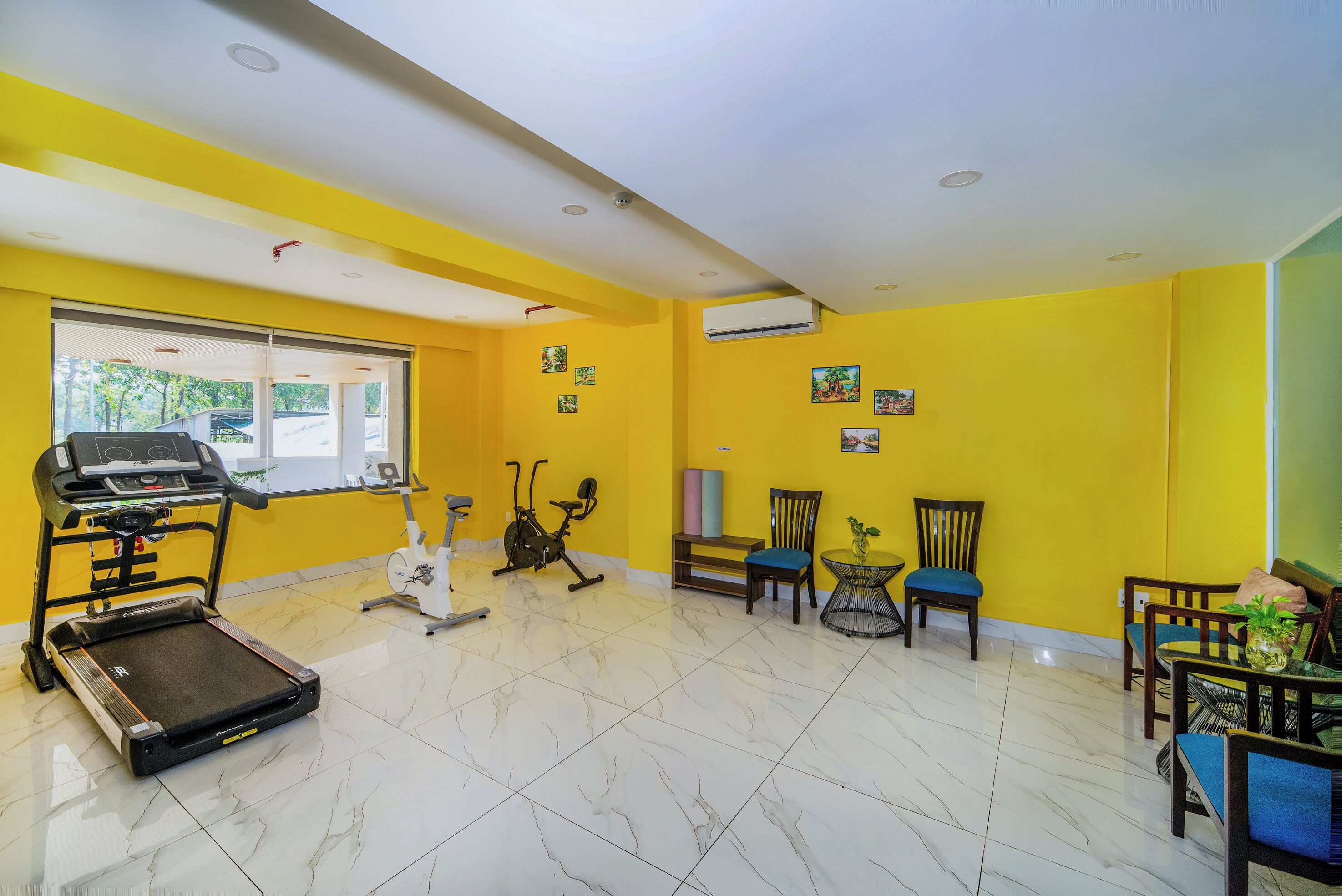 A fitness room with exercise equipment, a treadmill, stationary bikes, and chairs.