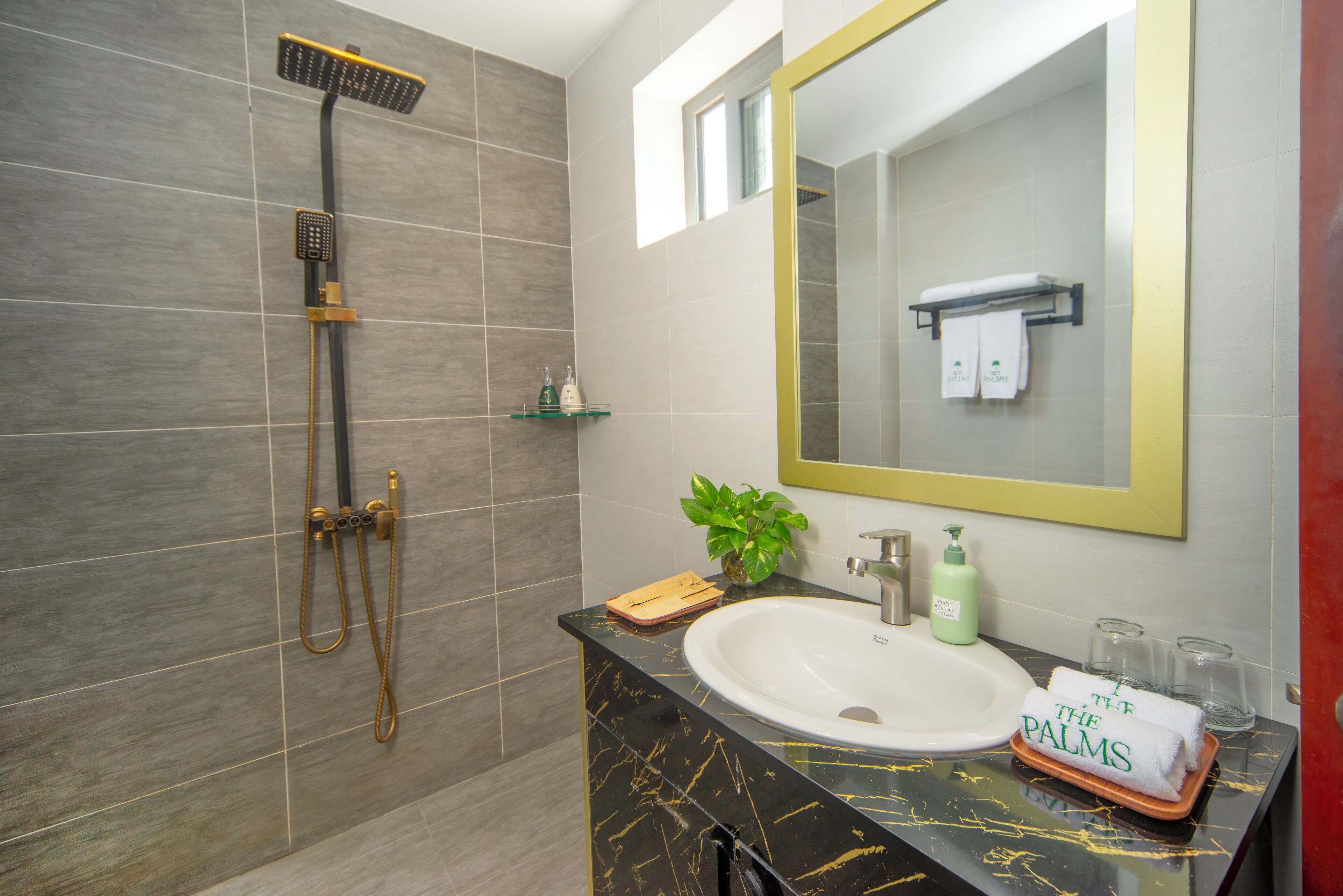 Een moderne badkamer met een zwart marmeren wastafel, een grote spiegel en een douche met een handdouche.