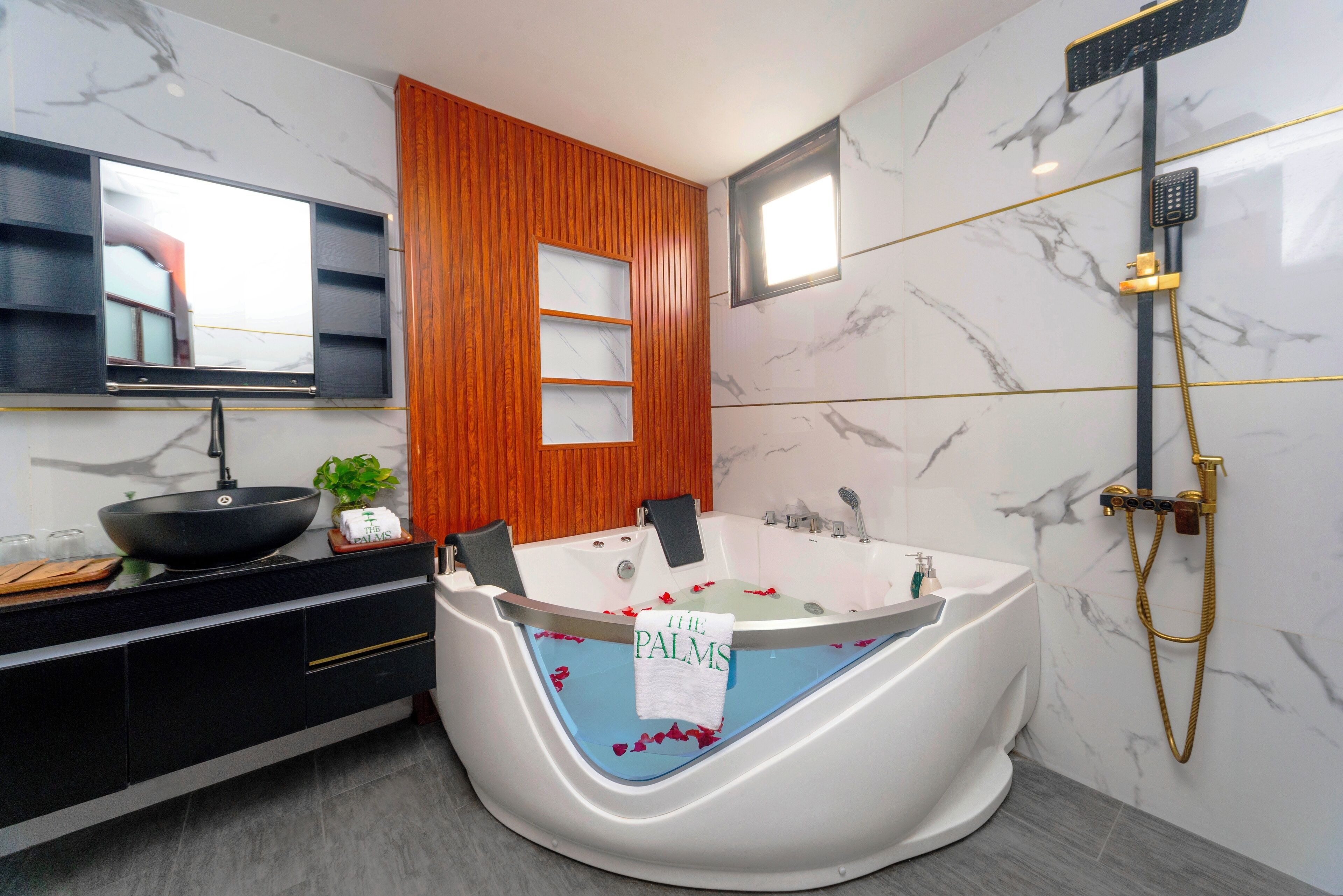 Et moderne badeværelse med et fristående badekar, et toiletbord med en sort vask og en væg beklædt med træpaneler.