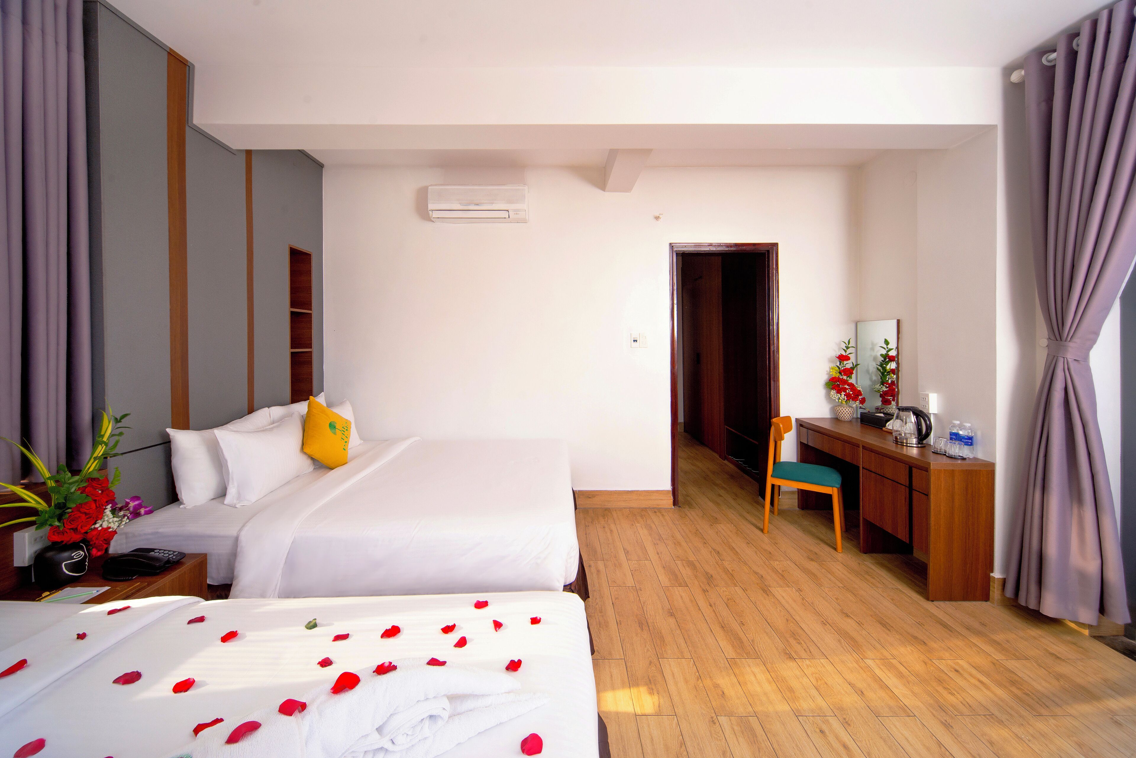 A hotel room with two beds, a desk, a chair, and a wardrobe.