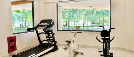 A gym with a treadmill, an elliptical, and a stationary bike.
