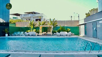 Una piscina al aire libre, sombrillas, sillones reclinables de piscina