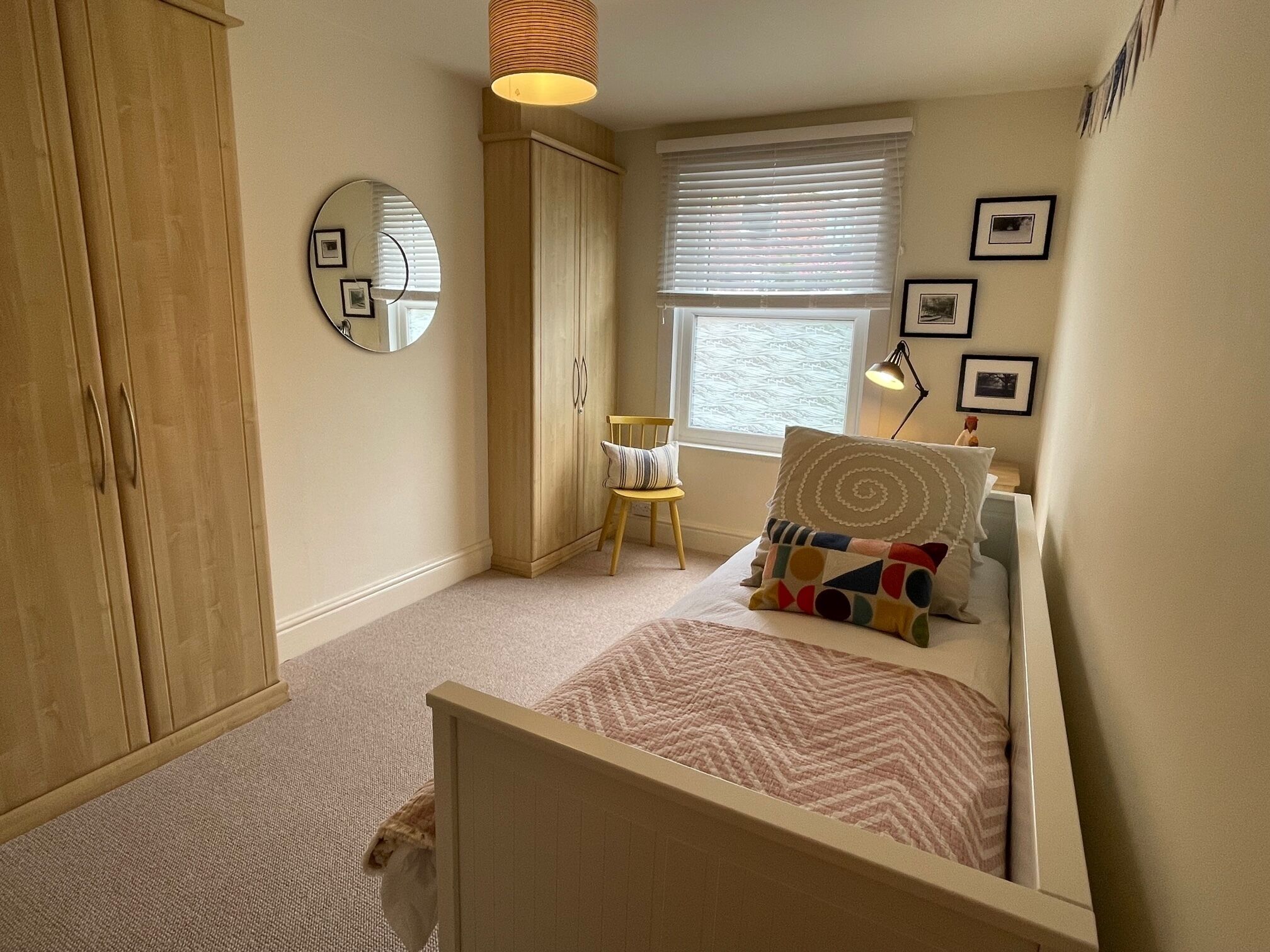 Une chambre à coucher comprenant un lit, une chaise, une armoire, une fenêtre et un miroir.