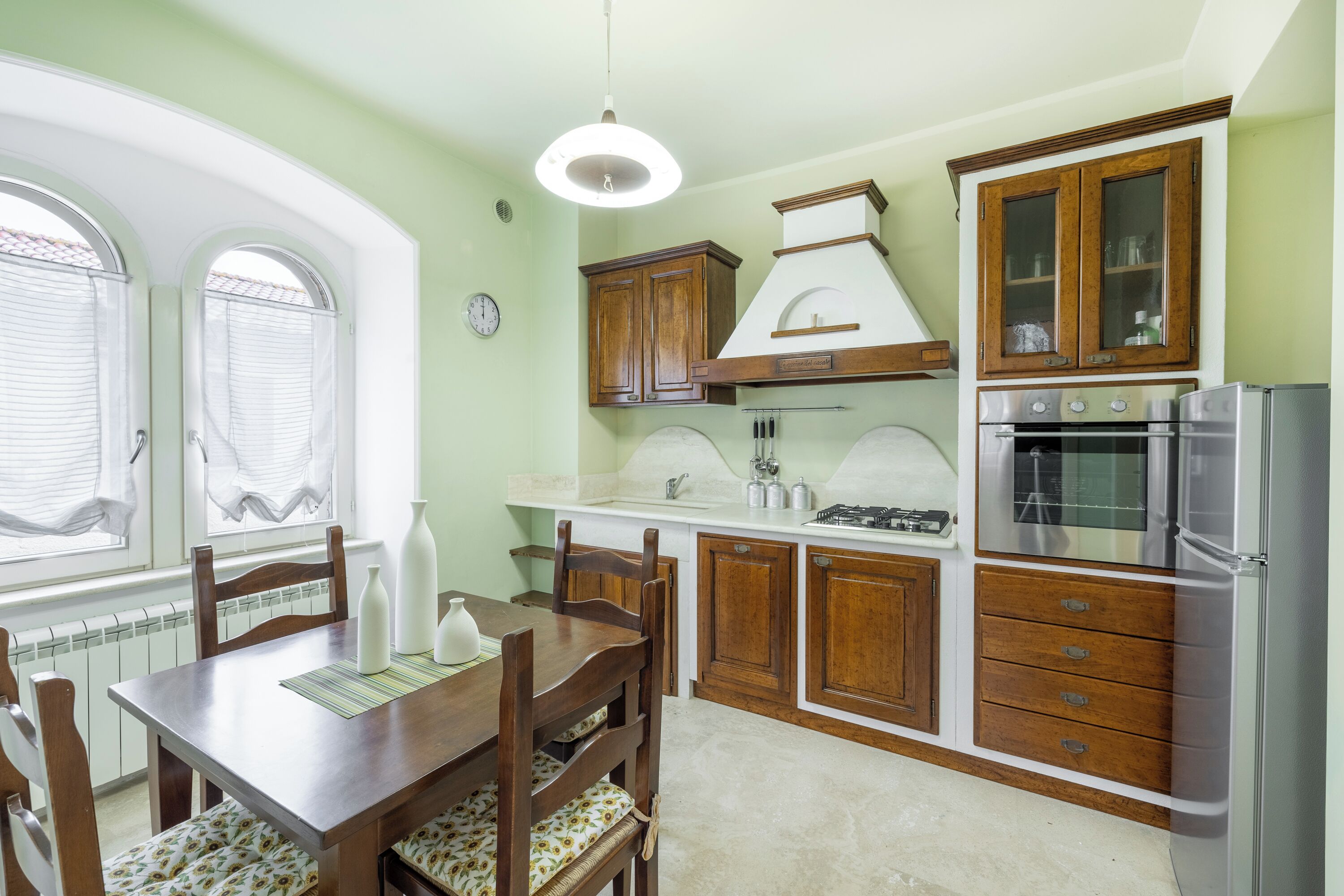 A kitchen with wooden cabinets, a white countertop, and a stainless steel refrigerator.
