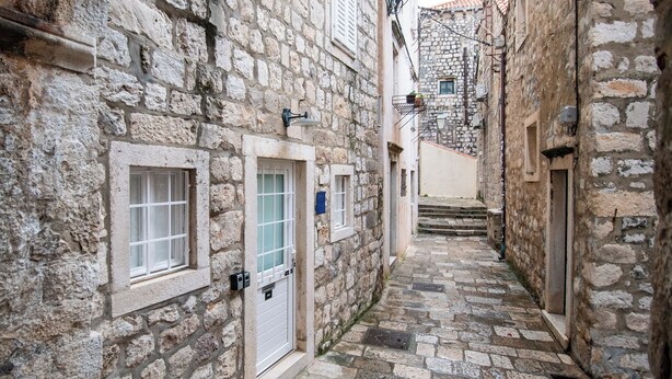 A narrow stone-paved alleyway with stone buildings on either side, featuring doorways and windows. - Luan Old Town apartment by DuHomes (Dubrovnik)