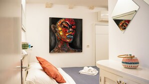 A hotel room with a bed, a painting on the wall, a mirror, and a small table with a decorative item. - Luan Old Town apartment by DuHomes (Dubrovnik)