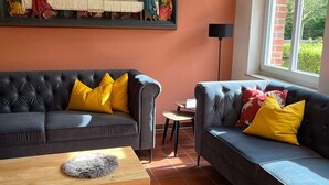 Een woonkamer met een groot schilderij, twee banken, een salontafel en een raam met uitzicht.